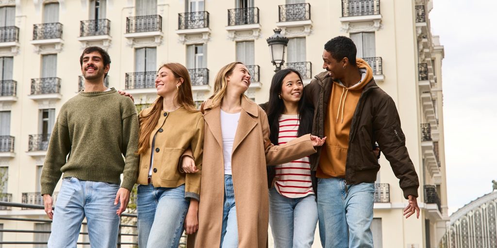 five happy young multi ethnic friends walking together in the city,